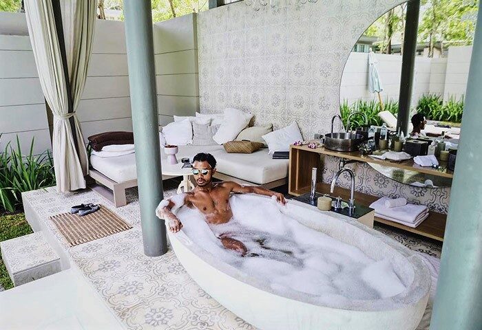 Gay man in bubble bath at SALA Phuket Mai Khao Beach Resort. Luxury gay-friendly hotel in Phuket, Thailand. Relaxing vacation.