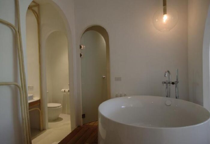 Bathroom at SALA Samui Chaweng Beach, a gay-friendly hotel. Features a round tub, toilet, & frosted glass door. Modern design for gay travelers.
