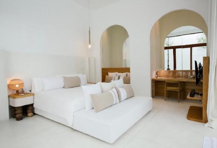 SALA Samui Chaweng Beach gay-friendly hotel room. Modern design with a bed, desk, and arched doorways. Minimalist, bright, and airy.