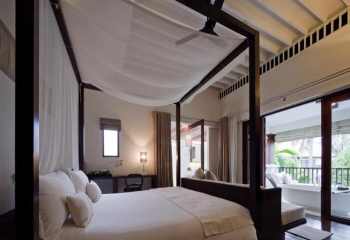 Bedroom at SALA Samui Choengmon Beach, a gay-friendly hotel. Four-poster bed with white linens, balcony with tub. Luxury travel.