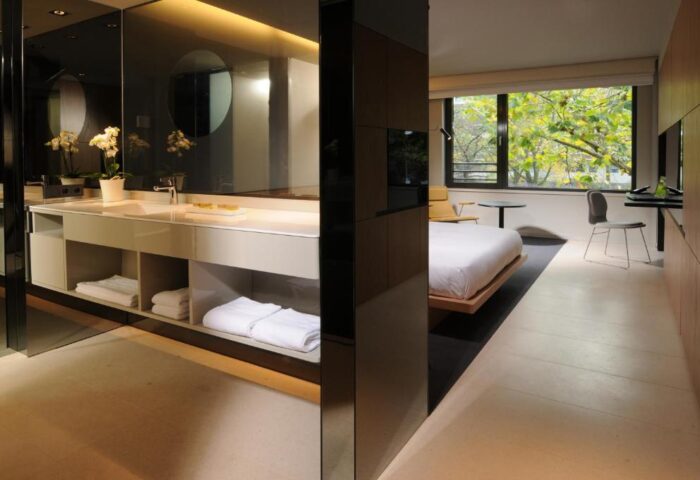 SANA Berlin Hotel's gay-friendly, pet-friendly room. Modern design with a bathroom vanity, towels, and a view of trees outside the window.