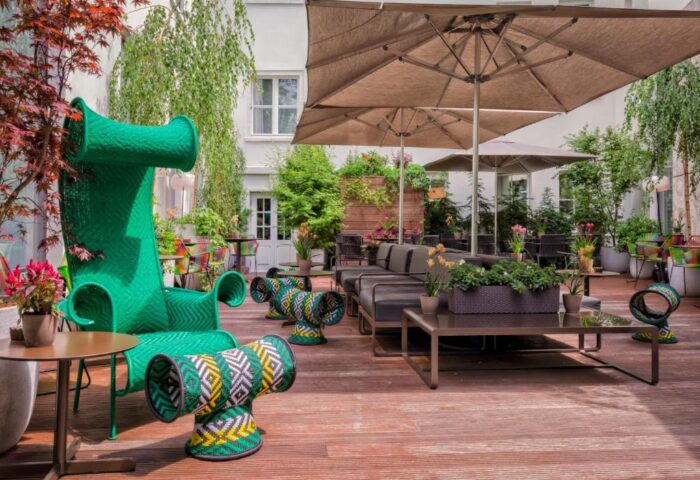 SO/ Berlin Das Stue gay-friendly hotel's pet-friendly outdoor lounge area with unique green furniture and umbrellas. Stylish and inviting.