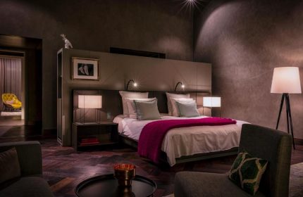 SO/ Berlin Das Stue gay-friendly hotel room. Pet-friendly hotel with a bed, bedside tables, lamps, and a chair. Luxury gay travel.