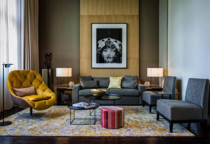 SO/ Berlin Das Stue hotel interior. Gay-friendly, pet-friendly hotel room with yellow chair, grey sofa, and modern art. Stylish Berlin stay.
