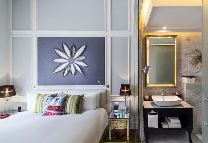 SO/ Sofitel Singapore, gay-friendly hotel room. Bed with flower art, nightstand, and bathroom with sink and mirror. Luxury style.
