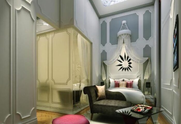 SO/ Sofitel Singapore, a gay-friendly hotel. View of a luxurious room with a canopy bed, stylish furniture, and a glimpse of the bathroom.