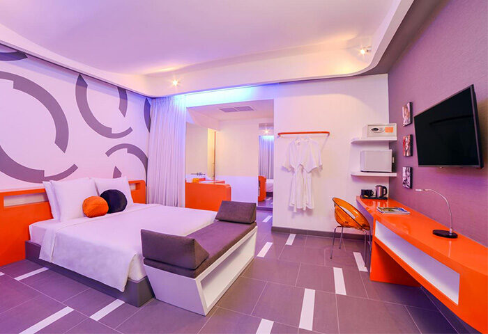 SUN & MOON Urban Hotel, gay-friendly room. Modern design with bed, orange accents, desk, and TV. Ideal for gay men travel, urban stay.