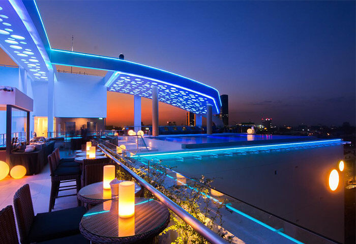 Rooftop pool at SUN & MOON Urban Hotel, a gay-friendly hotel. Features city views, blue lighting, tables, and chairs. Perfect for gay travel.