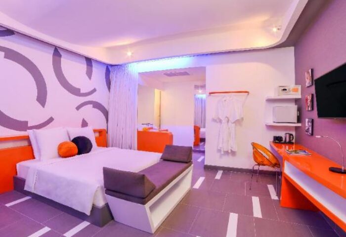 SUN & MOON Urban Hotel room. Gay-friendly hotel with bed, orange desk, and purple lighting. Modern design for gay men travelers.