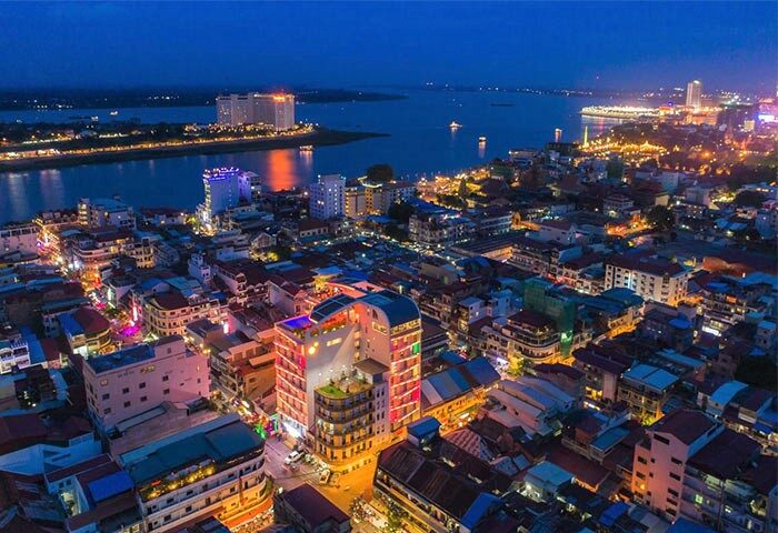 Night view of SUN & MOON Urban Hotel, a gay-friendly hotel. Cityscape with the hotel illuminated, river, and city lights. Gay travel destination.