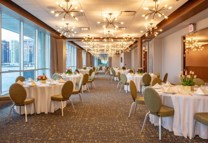 Sable at Navy Pier Chicago, Curio Collection by Hilton ballroom. Tables with white tablecloths, chairs, and centerpieces. Chandelier lighting.