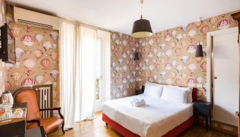 Salotto Monti gay-friendly hotel room. Bedroom with hot air balloon wallpaper, double bed, chair, and wooden floor. Gay travel lodging.