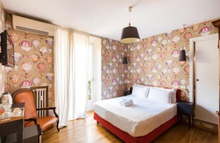 Salotto Monti gay-friendly hotel room. Bedroom with hot air balloon wallpaper, double bed, chair, and wooden floor. Gay travel lodging.
