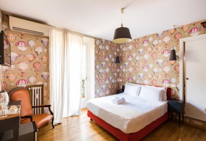 Salotto Monti gay-friendly hotel room. Bedroom with hot air balloon wallpaper, double bed, chair, and wooden floor. Gay travel lodging.