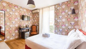 Salotto Monti gay-friendly hotel room. Double bed, hot air balloon wallpaper, desk, chair, and balcony. Gay travel in Rome, Italy.