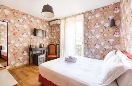 Salotto Monti gay-friendly hotel room. Double bed, hot air balloon wallpaper, desk, chair, and balcony. Gay travel in Rome, Italy.