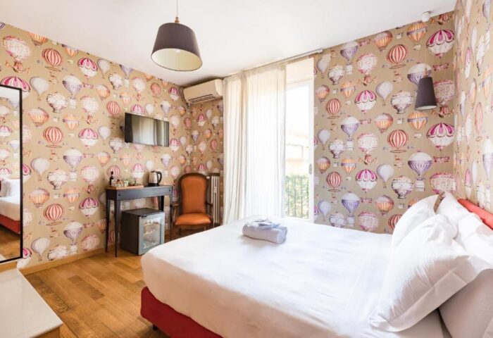 Salotto Monti gay-friendly hotel room. Double bed, hot air balloon wallpaper, desk, chair, and balcony. Gay travel in Rome, Italy.
