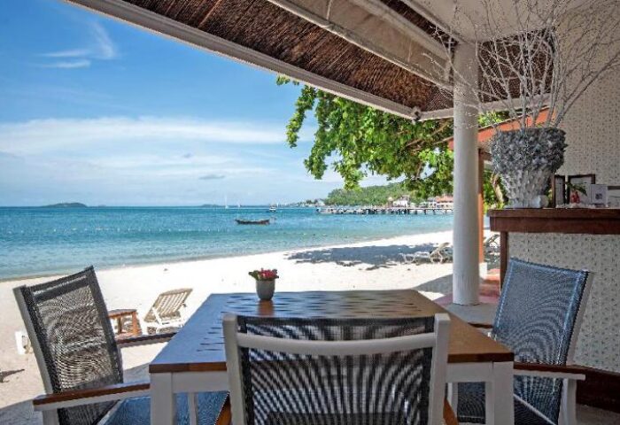 Samed Club Resort gay-friendly hotel: Beachfront dining area with ocean view. Table and chairs on the sand, perfect for a relaxing vacation.