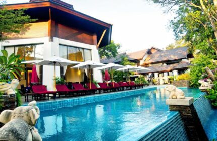 Samed Pavilion Resort pool view. Gay-friendly hotel with sun loungers, umbrellas, and elephant statues. Ideal for gay men travel.
