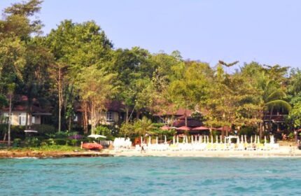 Samed Villa Resort: Gay-friendly hotel view. Beachfront villas with umbrellas, trees, and turquoise water. Ideal gay travel destination.