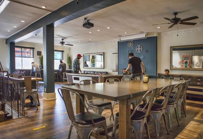 Samesun Hollywood, formerly Walk of Fame Hostel, gay-friendly hotel. Interior view with pool table, dining table, and guests. Relaxed atmosphere.
