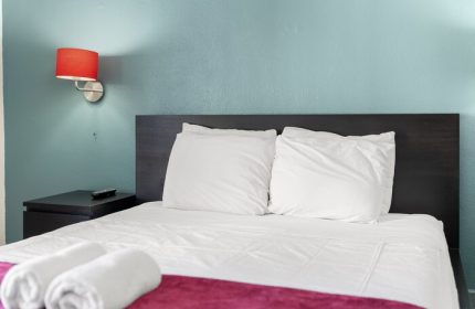 Samesun Hollywood hotel room, formerly Walk of Fame Hostel. Clean room with bed, pillows, towels, and red lamp. Gay-friendly hotel.
