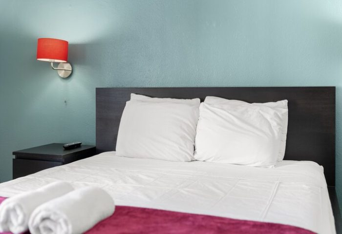 Samesun Hollywood hotel room, formerly Walk of Fame Hostel. Clean room with bed, pillows, towels, and red lamp. Gay-friendly hotel.