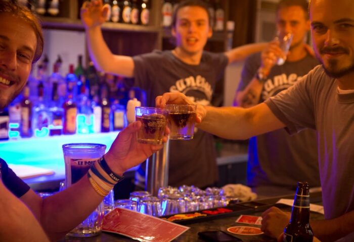 Gay-friendly Samesun Montreal Central Hotel bar scene. Men toasting drinks, celebrating. Nightlife at the central hostel.