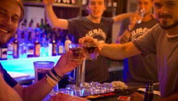 Gay-friendly Samesun Montreal Central Hotel bar scene. Men toasting drinks, celebrating. Nightlife at the central hostel.