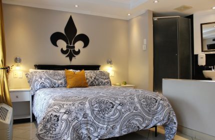 Samesun Montreal Central gay-friendly hotel room. King bed with paisley duvet, fleur-de-lis wall decor, and ensuite bathroom. Modern, clean design.