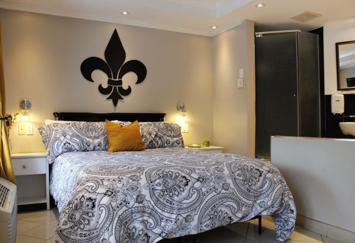 Samesun Montreal Central gay-friendly hotel room. King bed with paisley duvet, fleur-de-lis wall decor, and ensuite bathroom. Modern, clean design.