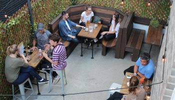 Samesun Montreal Central gay-friendly hotel outdoor patio. People at tables, enjoying drinks. Cozy, social atmosphere. Great for gay travelers.