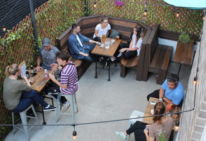 Samesun Montreal Central gay-friendly hotel outdoor patio. People at tables, enjoying drinks. Cozy, social atmosphere. Great for gay travelers.