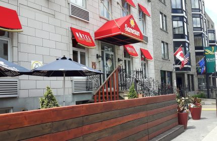 Samesun Montreal Central, a gay-friendly hotel. The building's facade has red awnings. Flags wave near this central Montreal hotel.