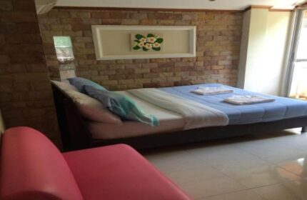 Samet Inn, gay-friendly hotel room. Interior shot of a bed with blue sheets and a pink chair in a room with brick walls. Gay travel advice.