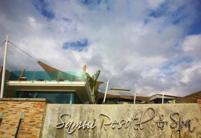 Samui Resotel Beach Resort entrance. Gay-friendly hotel in Samui, Thailand. Modern architecture, blue sky, and resort signage.