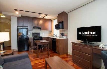 Sandman Suites Vancouver - Davie Street gay-friendly hotel room with kitchen, TV, and seating area. Ideal for gay men travel.