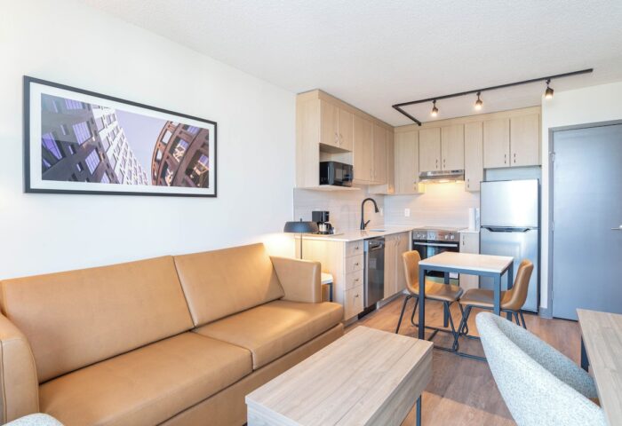 Sandman Suites Vancouver Davie Street gay-friendly hotel suite. Living area with sofa, kitchen, dining table. Modern design. Vancouver travel.