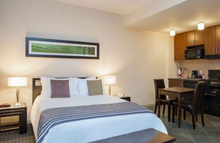 Sandman Suites Vancouver Davie Street gay-friendly hotel room. Queen bed, kitchenette, dining table, modern decor. Perfect for gay travel.