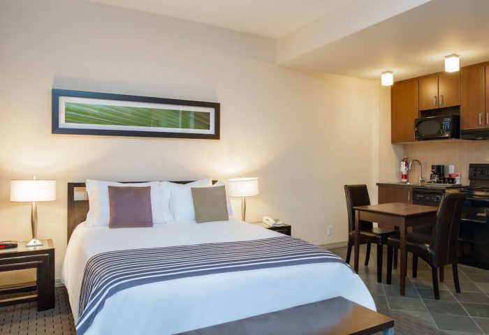 Sandman Suites Vancouver Davie Street gay-friendly hotel room. Queen bed, kitchenette, dining table, modern decor. Perfect for gay travel.