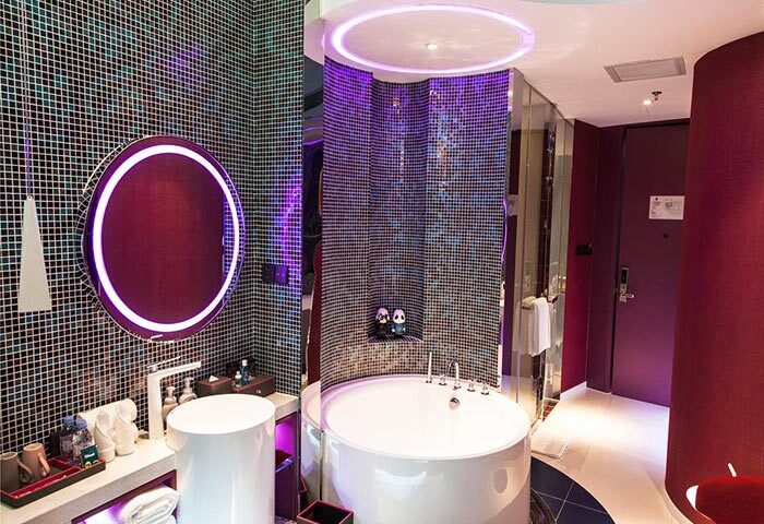 Bathroom at Sanlitun Mark Jacobs Boutique Hotel, a gay-friendly hotel. Features a round tub, mosaic tiles, & neon lighting. Stylish design.