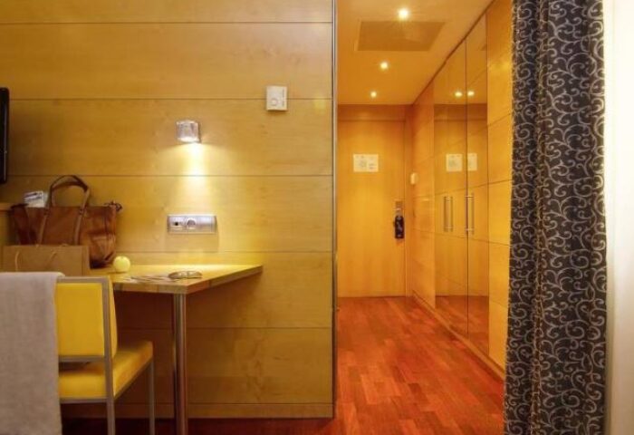 Sansi Diputacio Hotel's gay-friendly room. Features a desk, chair, wooden floor, and closet. A comfortable stay for gay travelers.