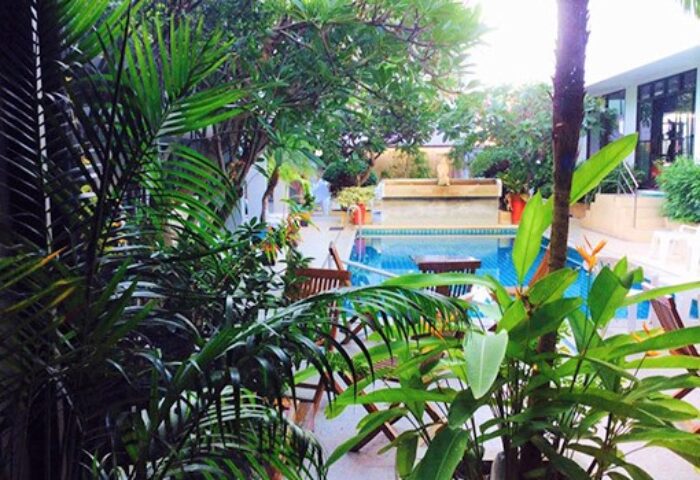 Sansuk Sauna Guesthouse pool view. Gay-friendly hotel featuring lush greenery, pool, lounge chairs, and a relaxing atmosphere. Sauna for gay men.