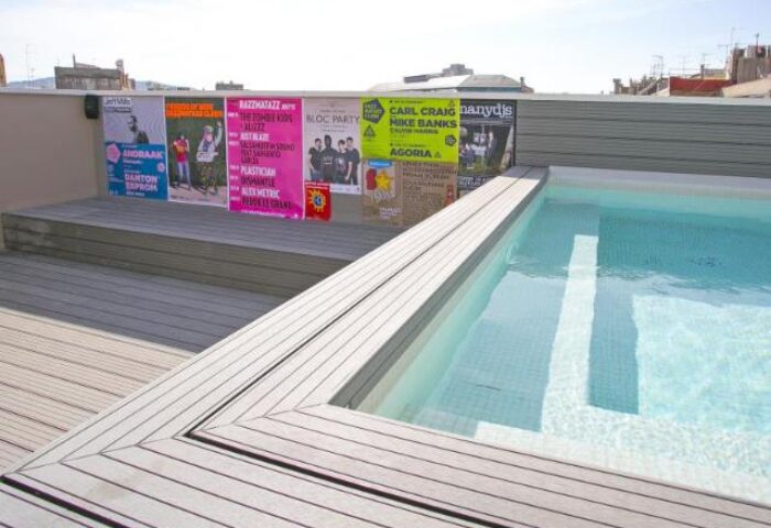 Rooftop pool at Sant Jordi Hostels Rock Palace, a gay-friendly hotel. Party posters add to the vibrant atmosphere for gay travelers.