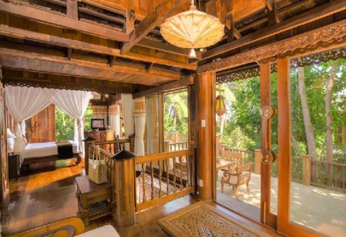 Santhiya Koh Phangan Resort & Spa interior. Gay-friendly hotel with wood accents, balcony, and bed. Tropical getaway for gay travelers.