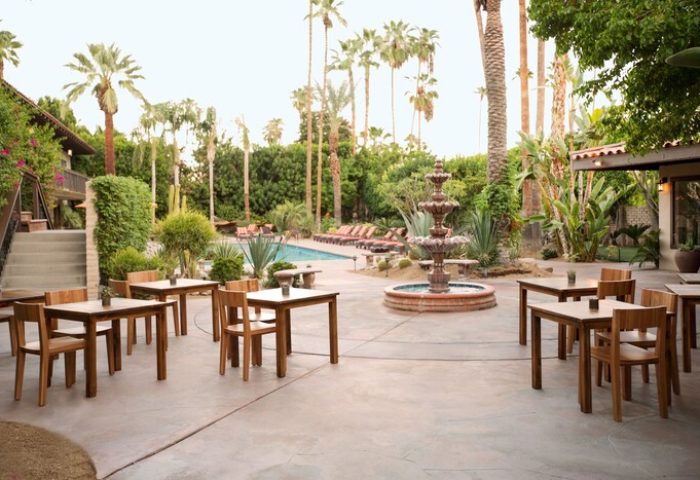 Santiago Resort Palm Springs premier gay men's resort outdoor dining area with pool, fountain, and palm trees. Gay-friendly hotel for travel advice.