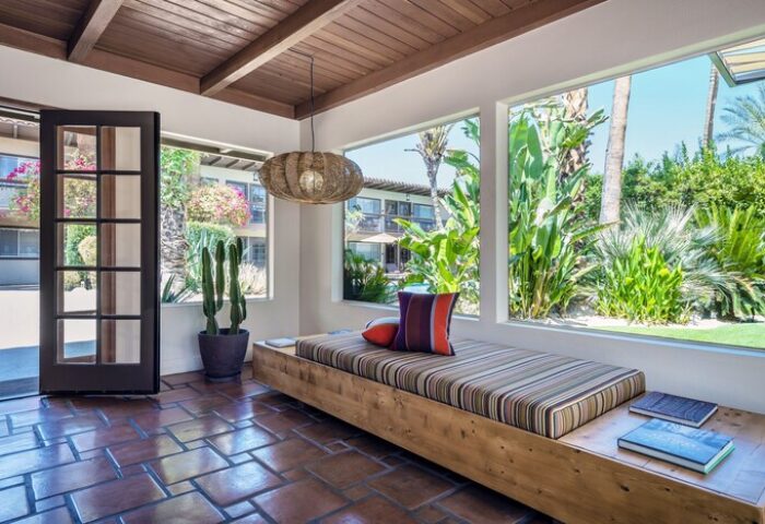 Interior of gay-friendly hotel Santiago Resort, Palm Springs. Daybed with pillows, view to garden. Premier gay men's resort.