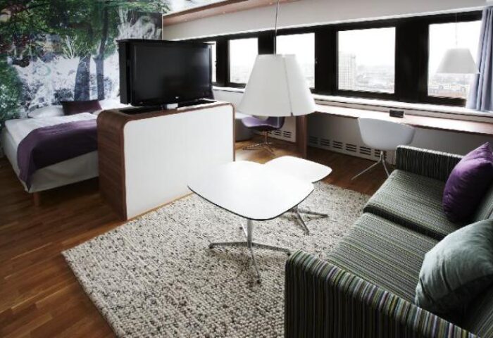 Scandic Copenhagen hotel room with bed, couch, and TV. Gay-friendly, pet-friendly hotel offers modern design and comfort for travelers.