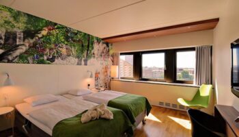 Scandic Copenhagen hotel room with twin beds, green accents, and a vibrant mural. Gay-friendly, pet-friendly hotel for gay travelers.