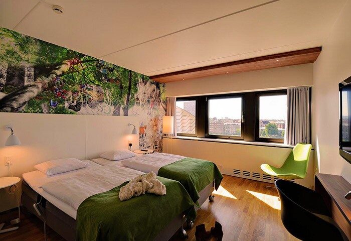 Scandic Copenhagen hotel room with twin beds, green accents, and a vibrant mural. Gay-friendly, pet-friendly hotel for gay travelers.